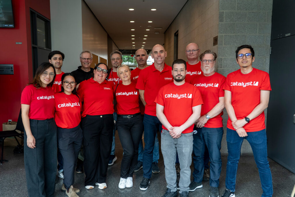 A group photo of staff members wearing red t-shirts with the Catalyst IT logo.